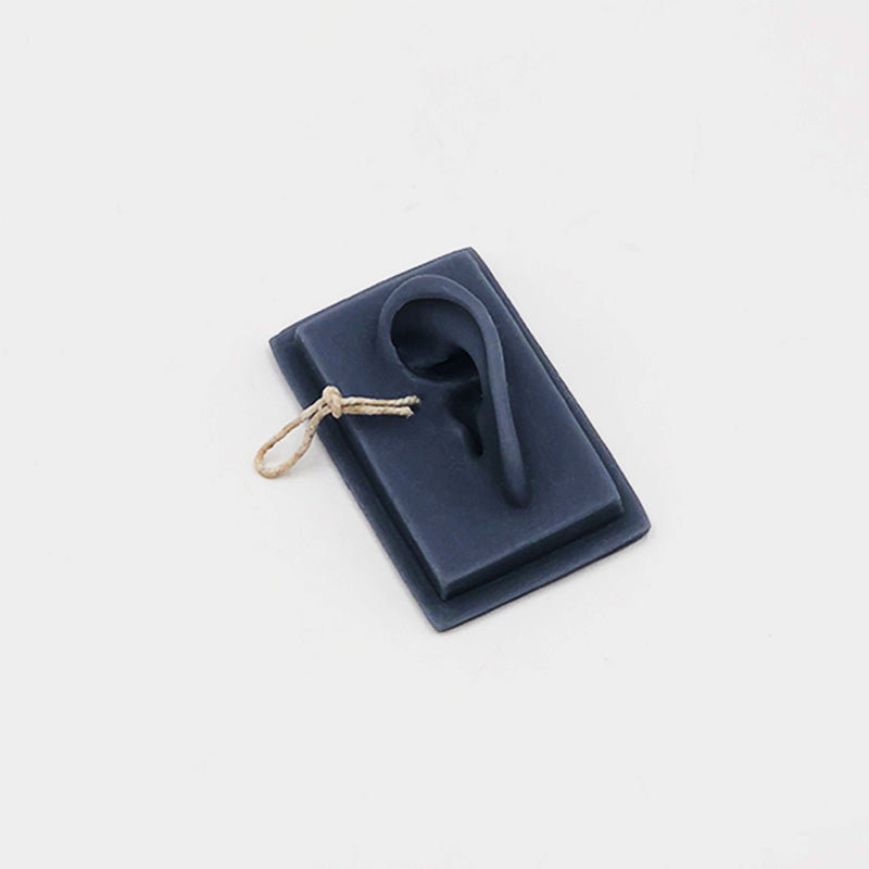 Navy blue silicone earring holder with a single earring on a light gray background