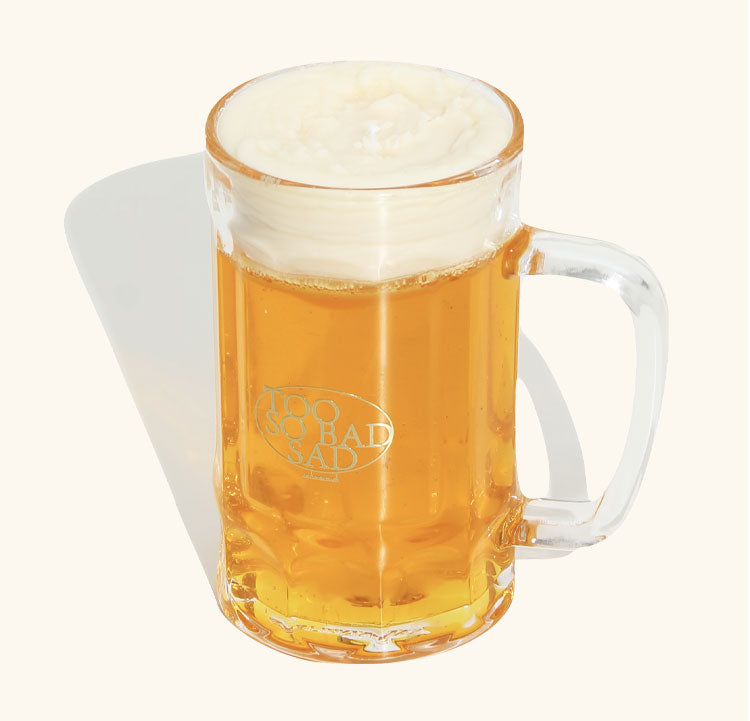 Clear glass mug with beer and 'Too Rad Sad' logo on a white background