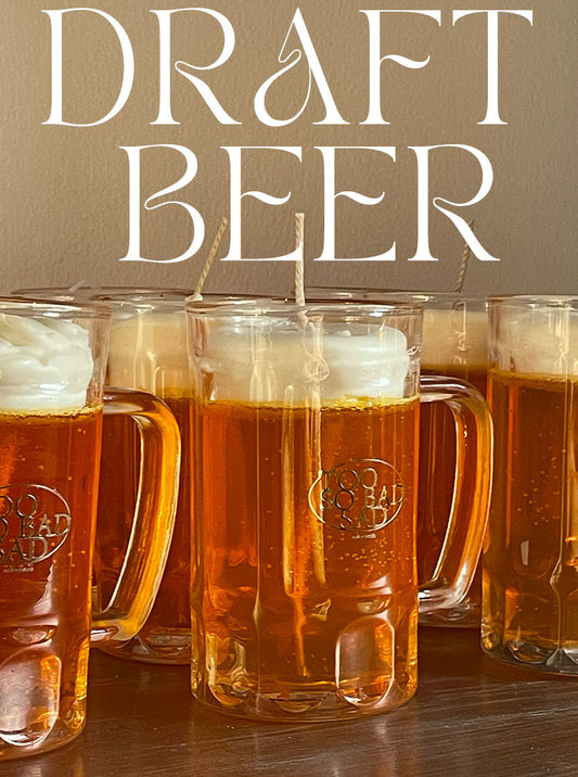 Row of glass mugs filled with beer on a wooden surface, with 'Draft Beer' text above.