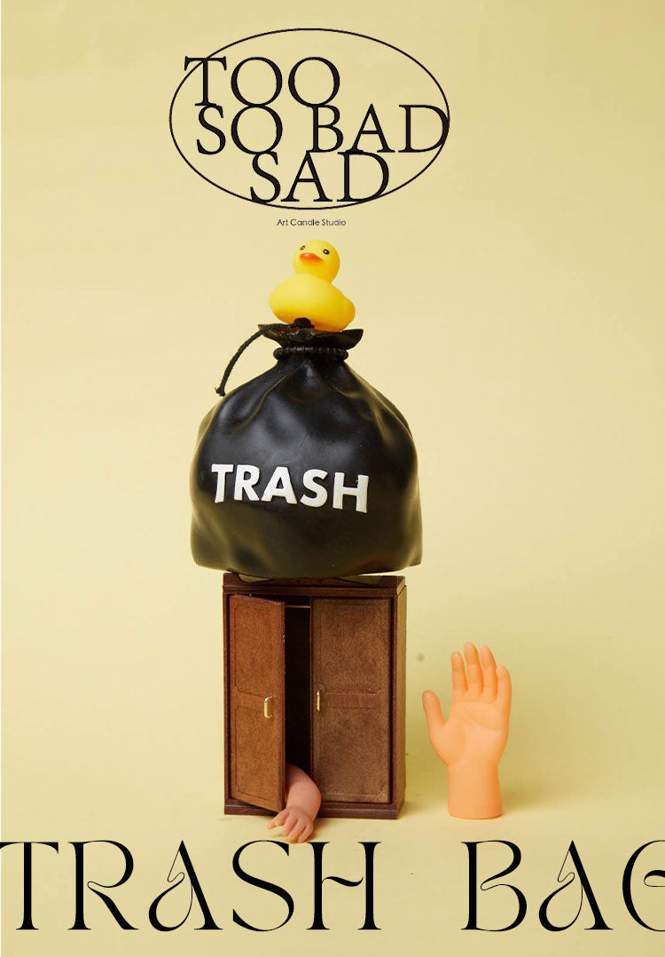 Black trash bag labeled 'TRASH' with a yellow duck and a foot emerging from it, on a beige background.