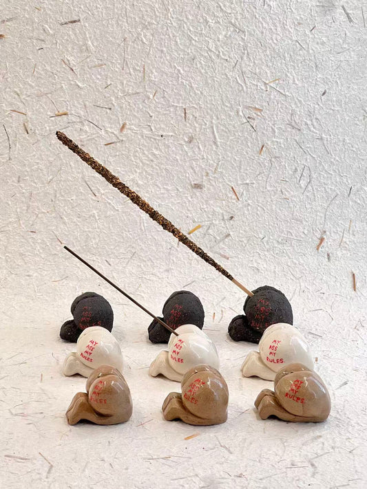 Set of small ceramic figures with incense sticks on a textured white surface