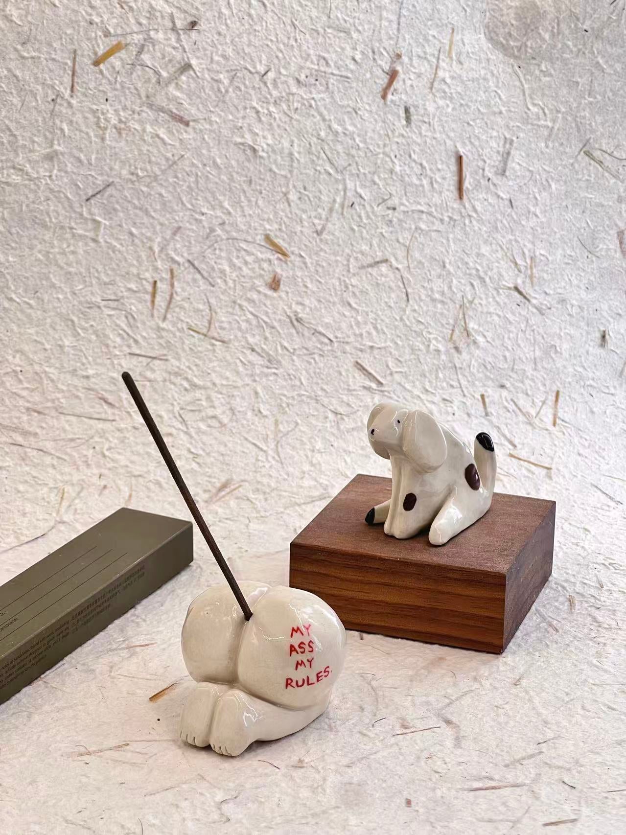 Decorative incense holder with text and a small figurine on a textured surface