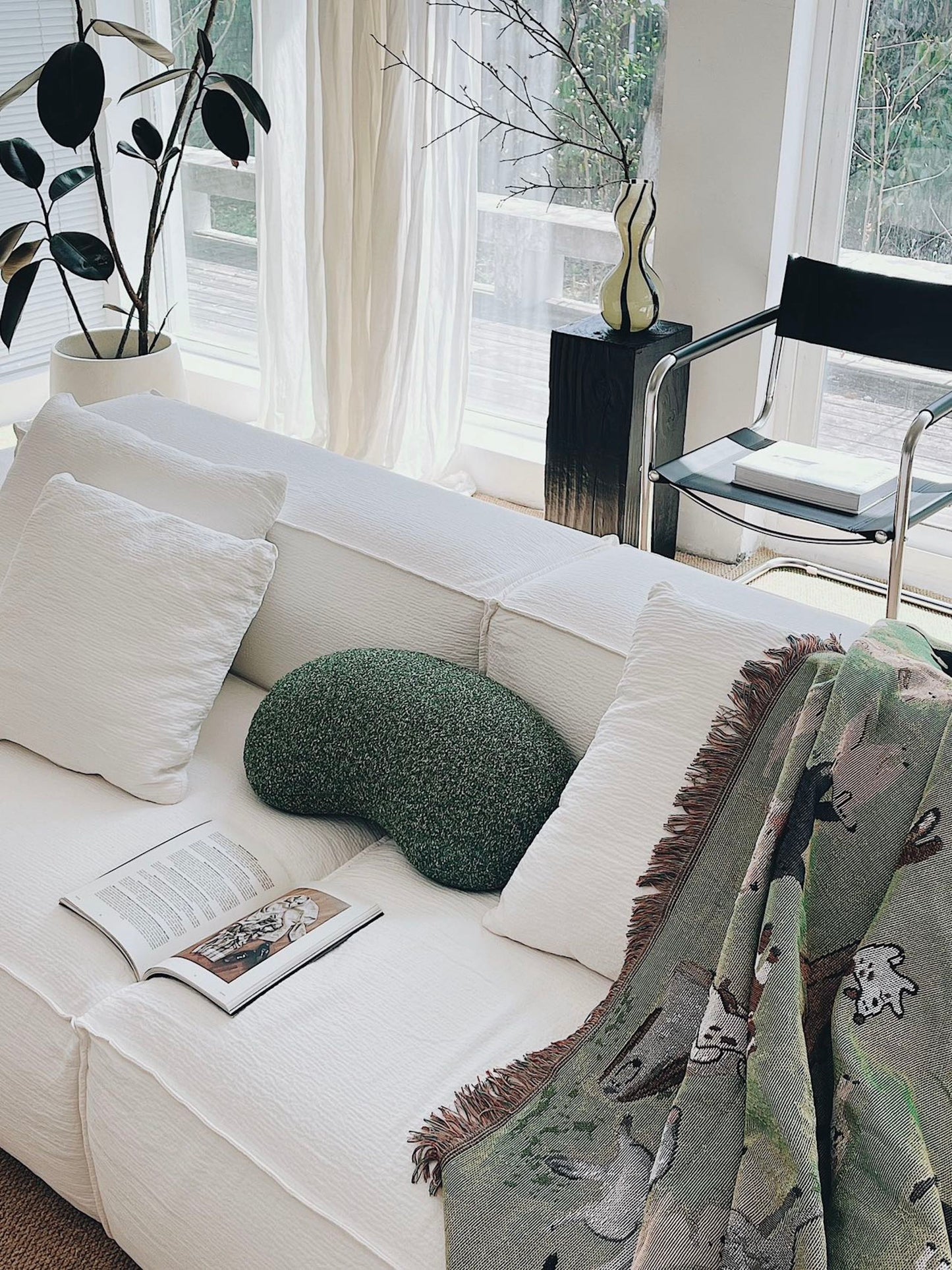 White sofa with decorative pillows and a blanket in a bright living room.
