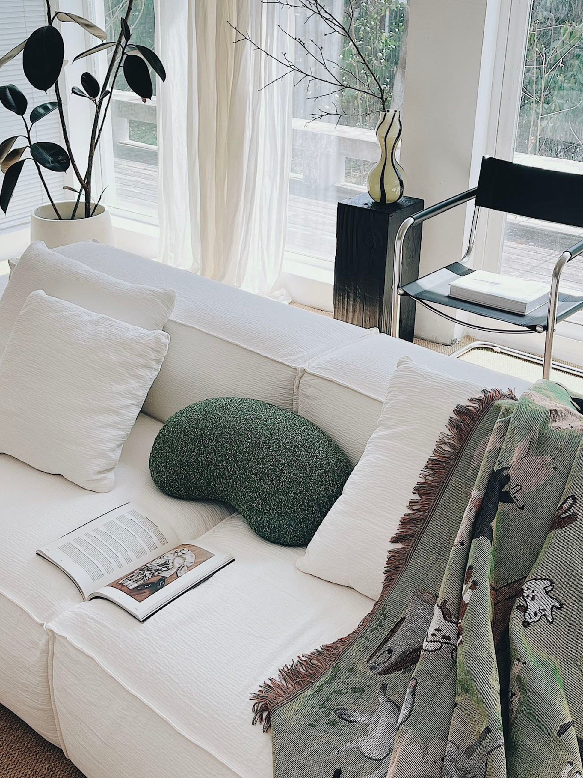 White sofa with decorative pillows and a blanket in a bright living room.