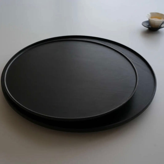 Black round tray on a white surface