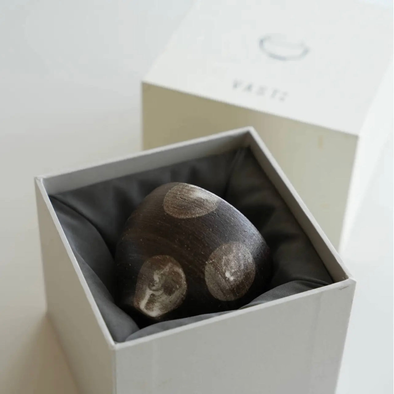 Gray stone with circular patterns inside a white box on a light gray background