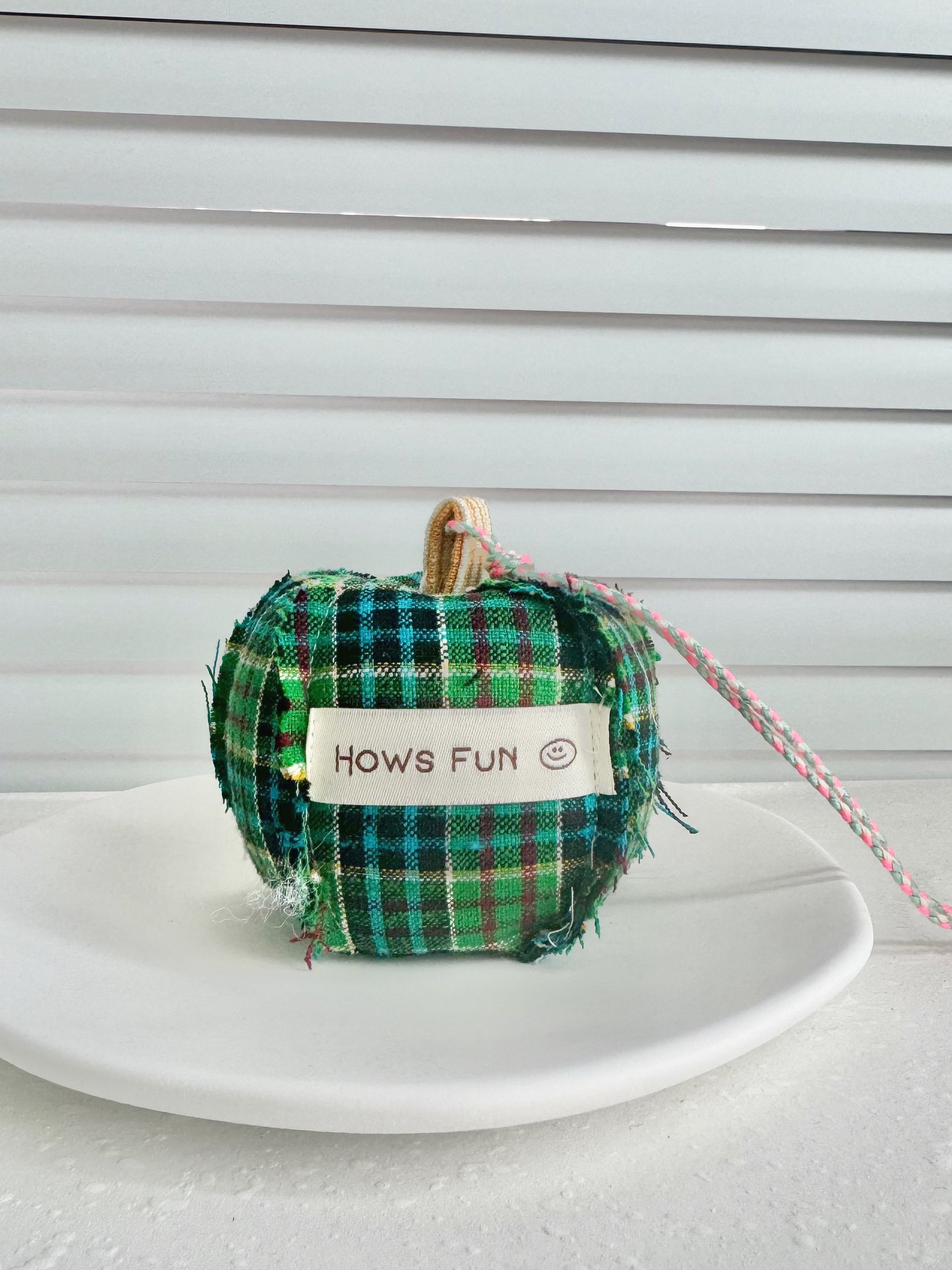 Green plaid fabric pumpkin with a label on a white surface