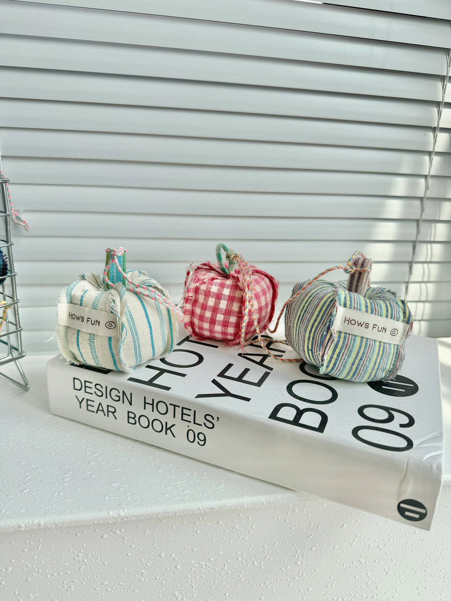 Three decorative pumpkins on a book with blinds in the background