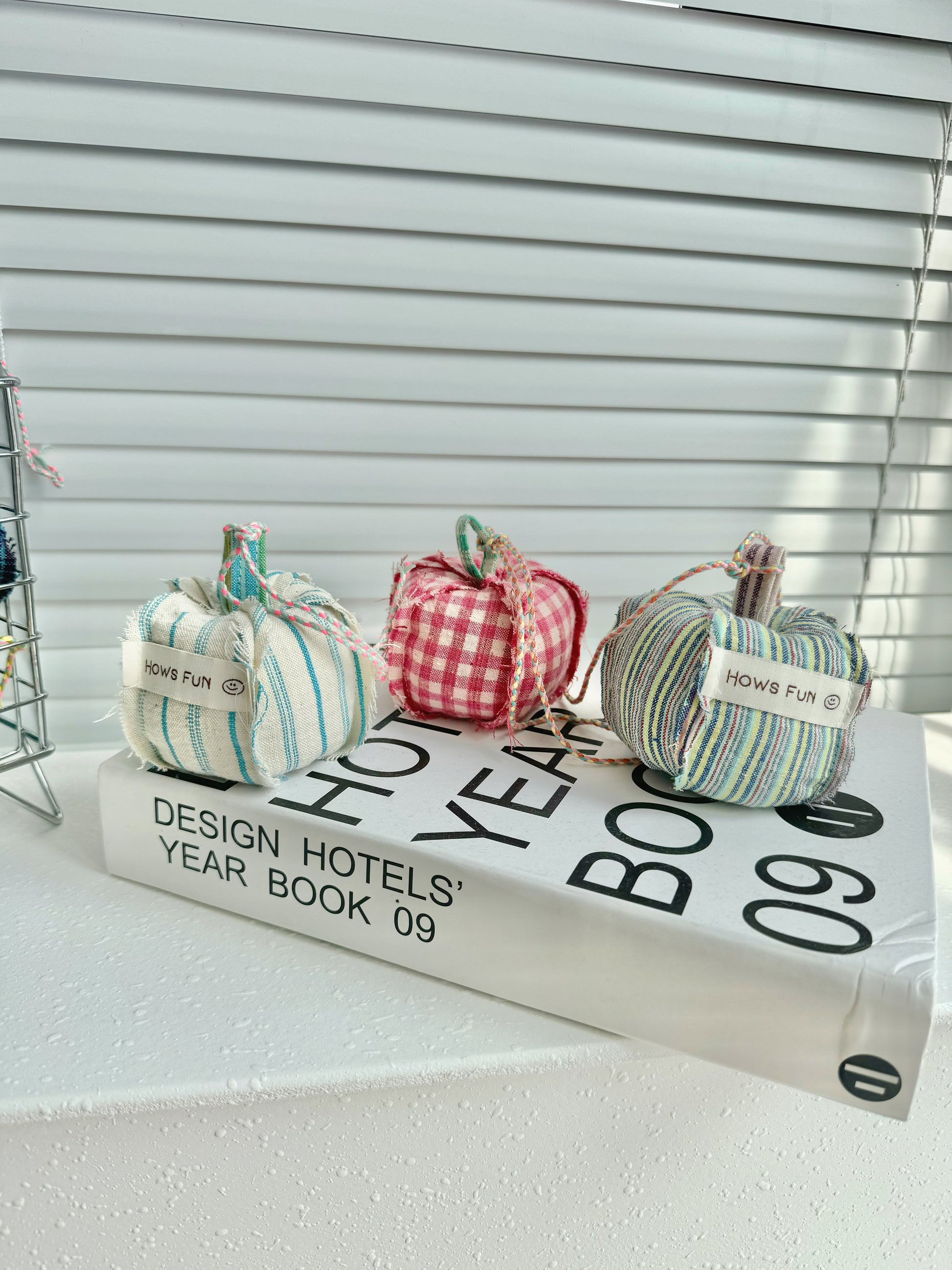 Three decorative pumpkins on a book with blinds in the background