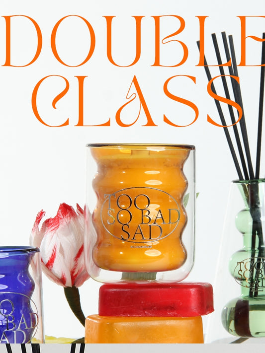 Candle with 'Bad Sia' branding and decorative items on a white background