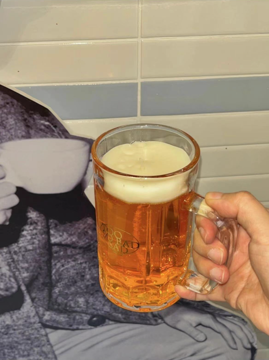 Person holding a mug of beer with a tiled wall background