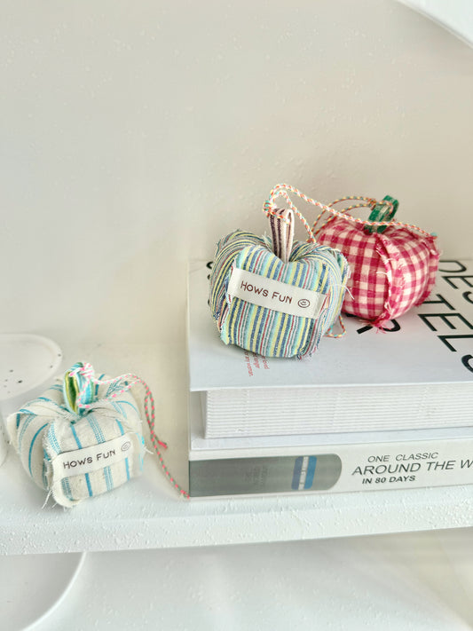 Small fabric pumpkins with 'How's Fun?' text on a white surface
