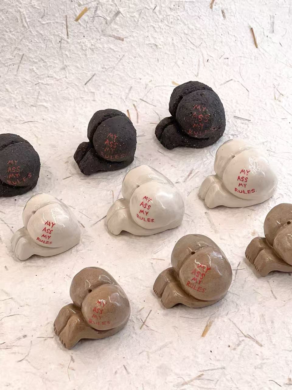 Collection of small ceramic figures with text on a textured white surface