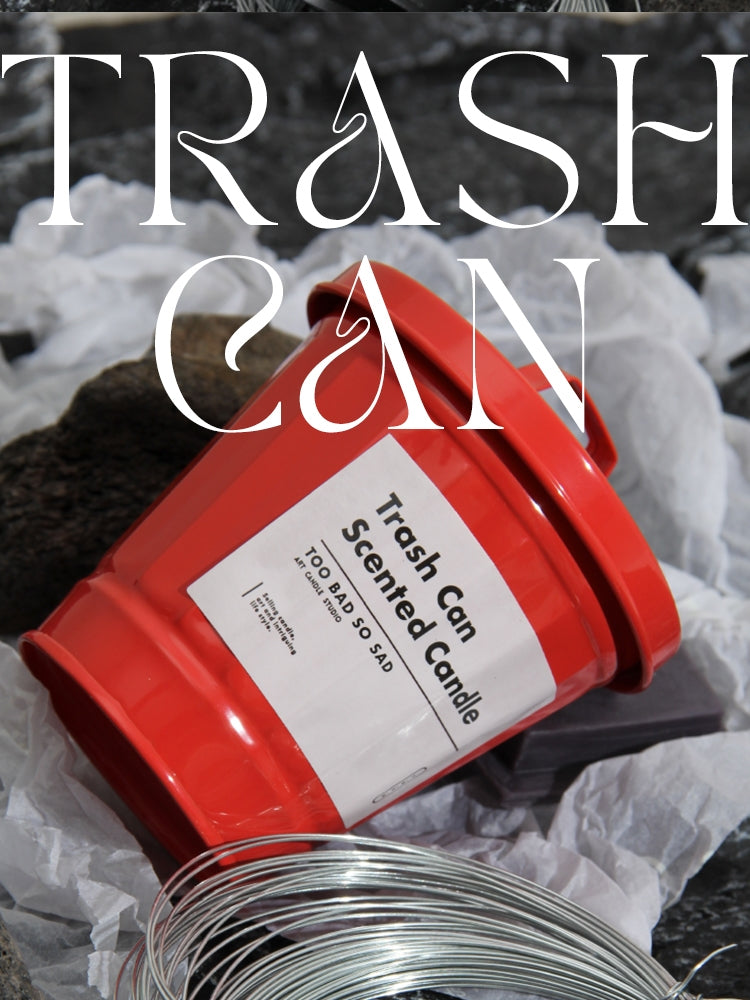 Red trash can-shaped candle with a label on a dark background