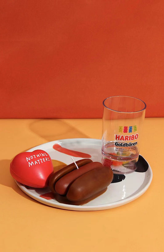 Haribo Goldbären chocolate bears and a glass on a white plate with an orange background