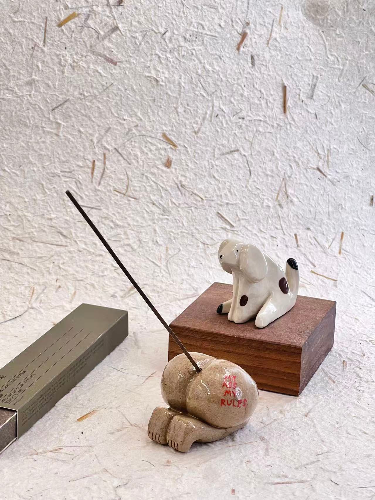 Ceramic dog incense holder with incense stick on a textured surface
