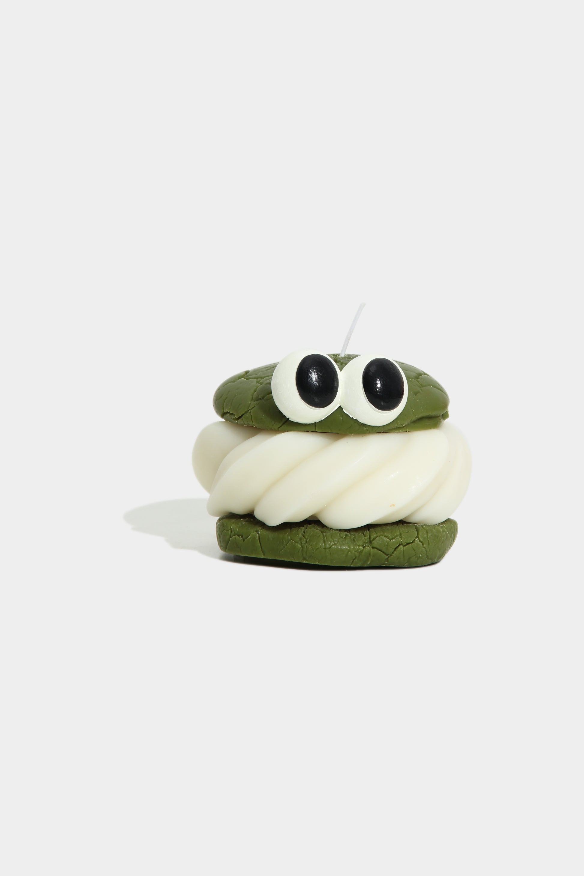 Small plush toy with a green body and white face on a light gray background