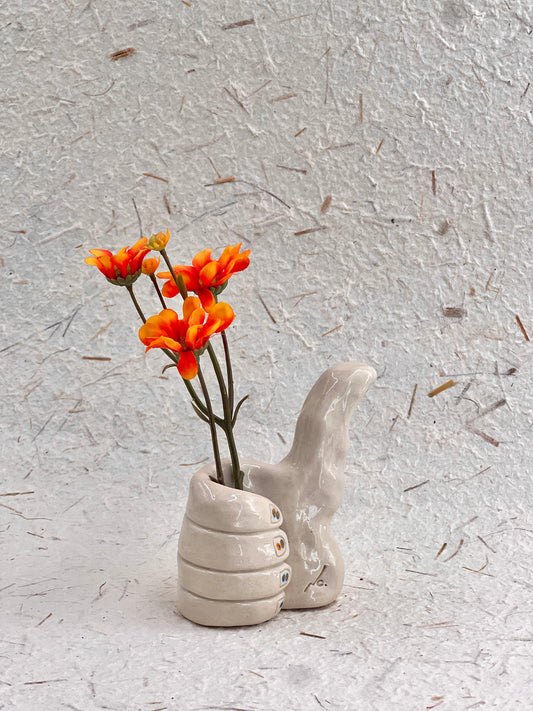 Ceramic vase with abstract design holding orange flowers on a textured gray background