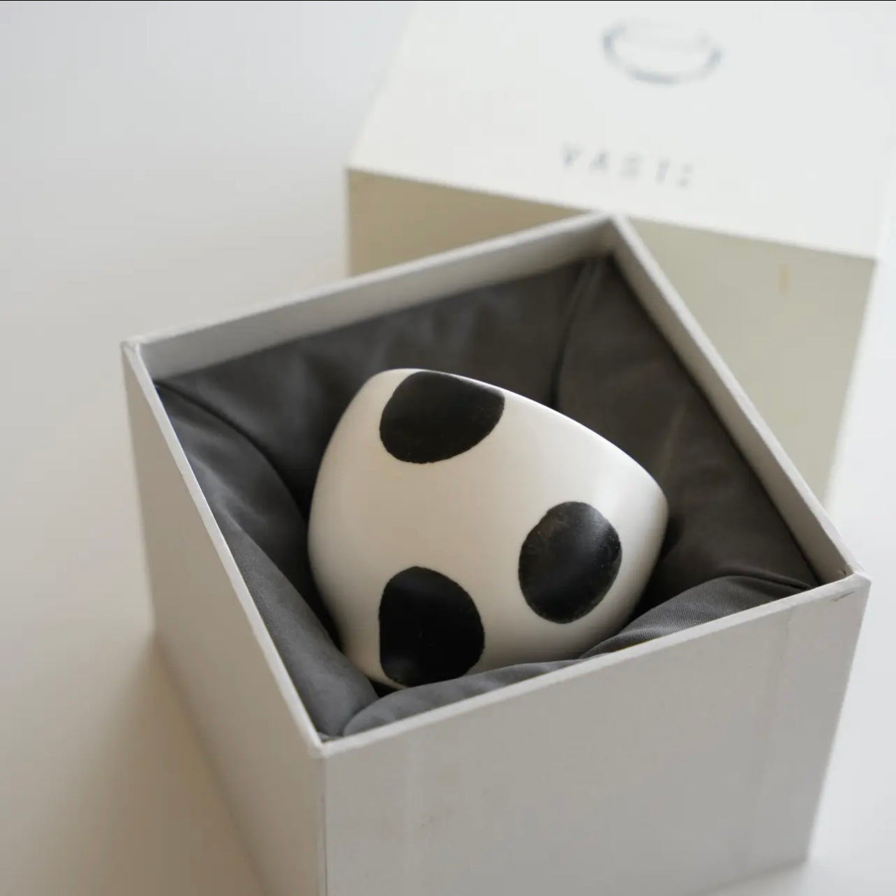 White ceramic object with black spots in a box