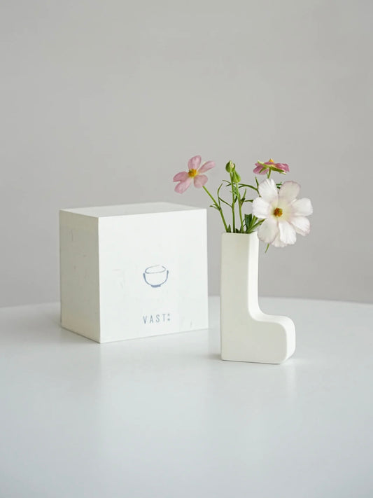 White vase with flowers on a gray surface and light gray background