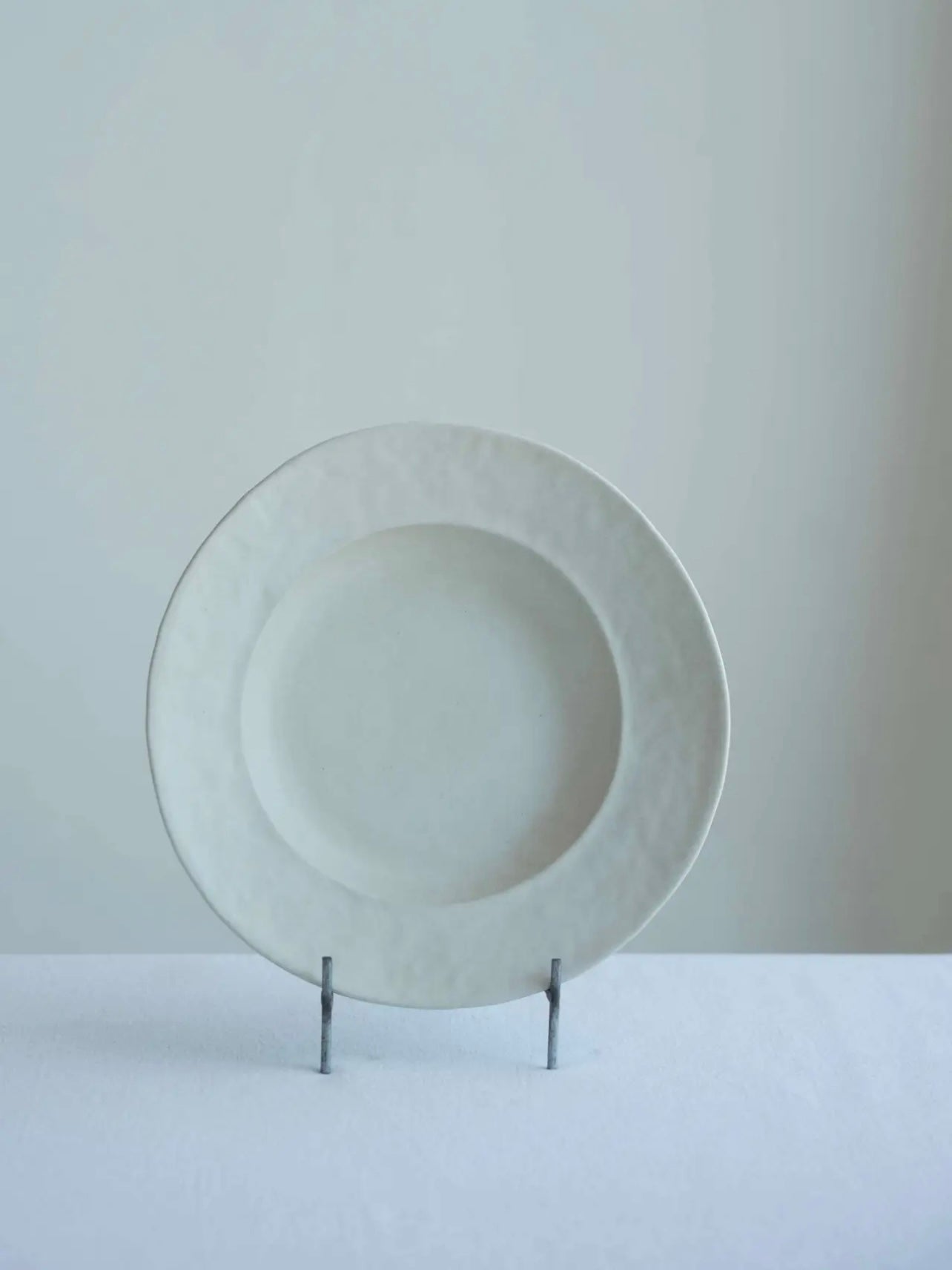 White ceramic plate on a stand against a light gray background