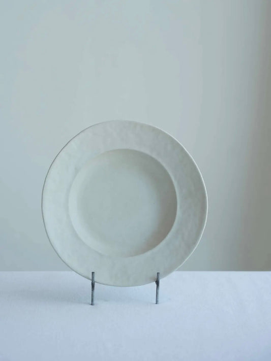 White ceramic plate on a stand against a light gray background
