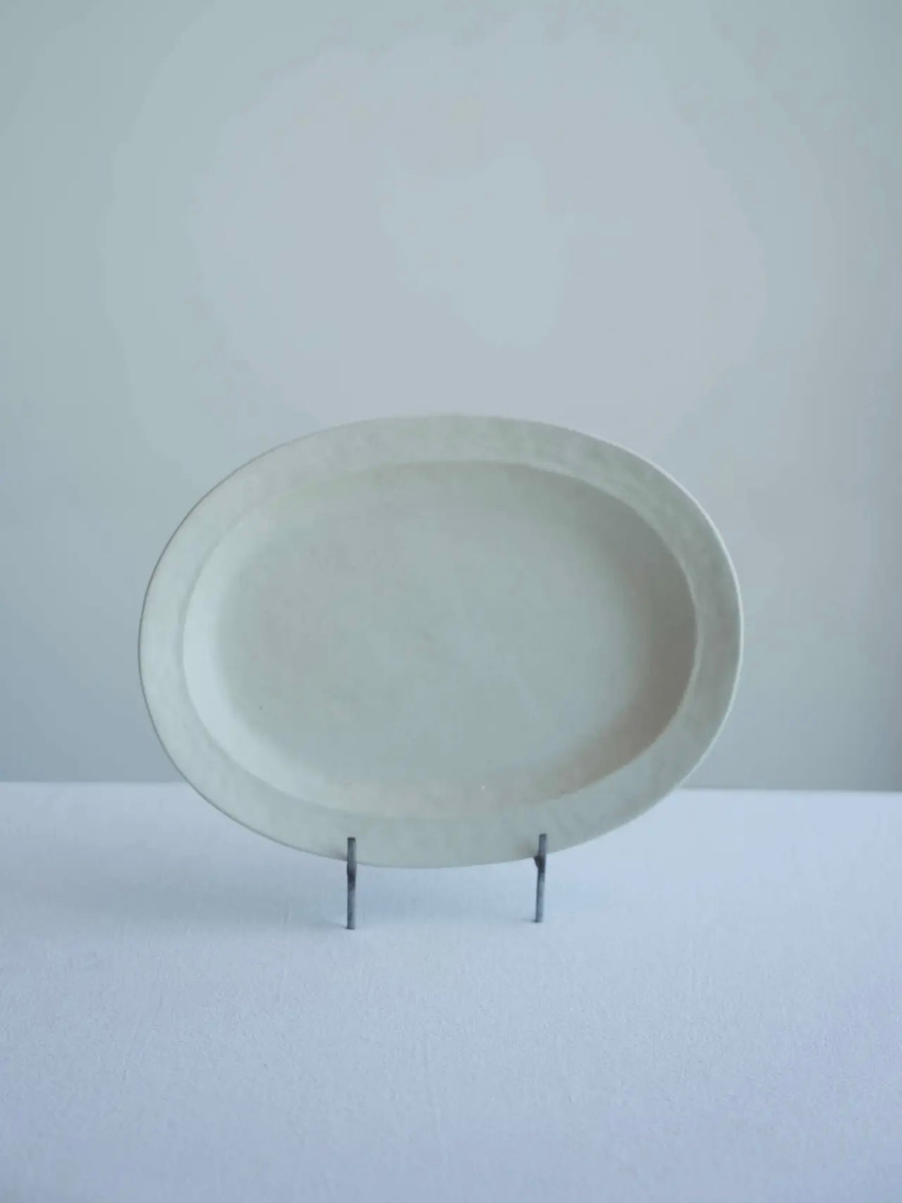 White ceramic plate on a stand against a light gray background