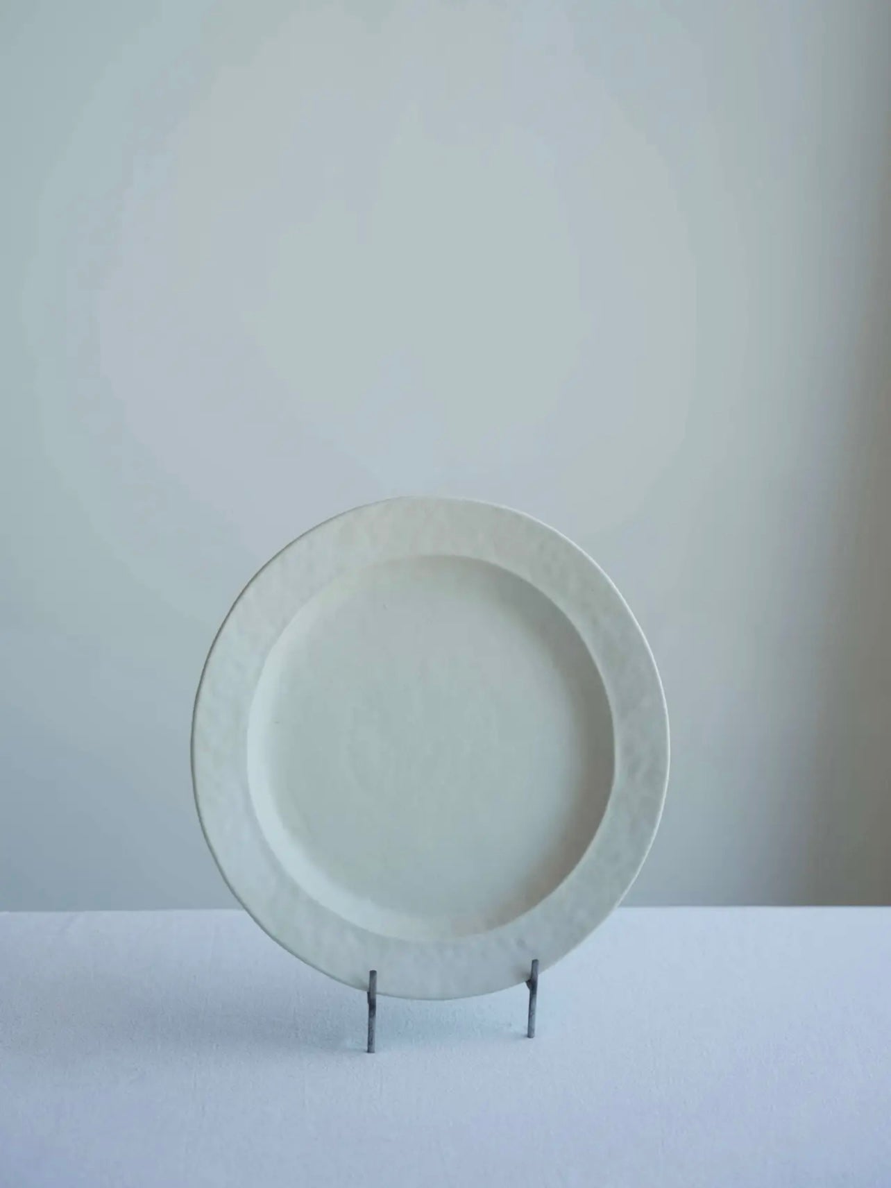 White ceramic plate on a stand against a plain background