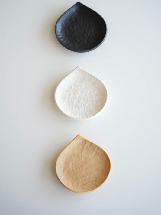 Three ceramic dishes in black, white, and beige on a light gray background