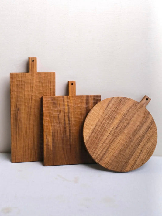 Three wooden cutting boards of different shapes and sizes on a light surface.