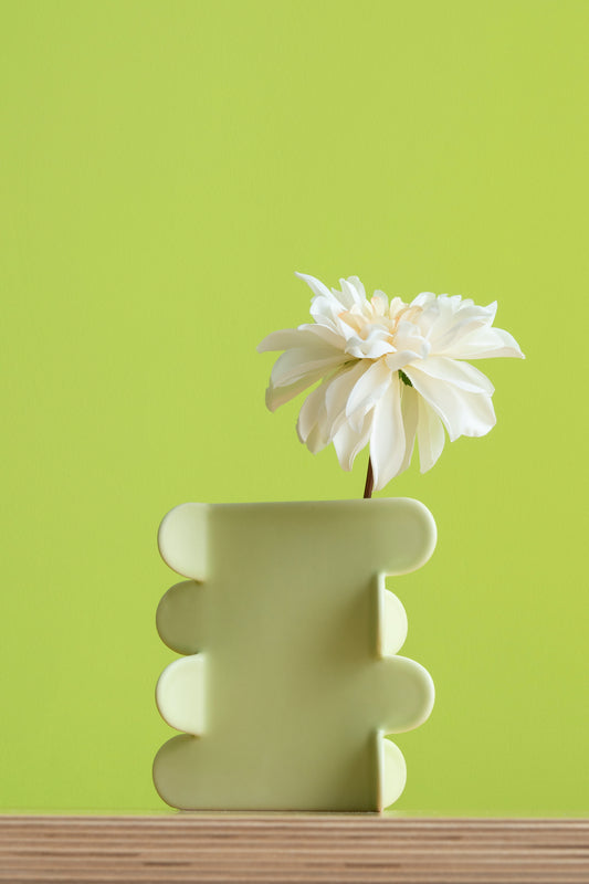 Decorative vase with a white flower against a green background