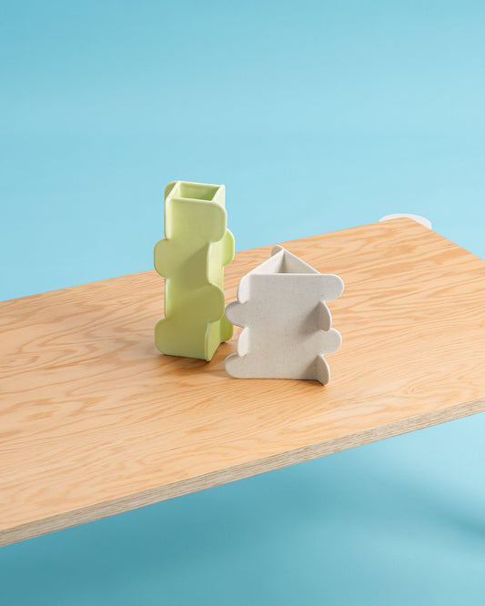 Two geometric-shaped cookie cutters on a wooden board with a blue background