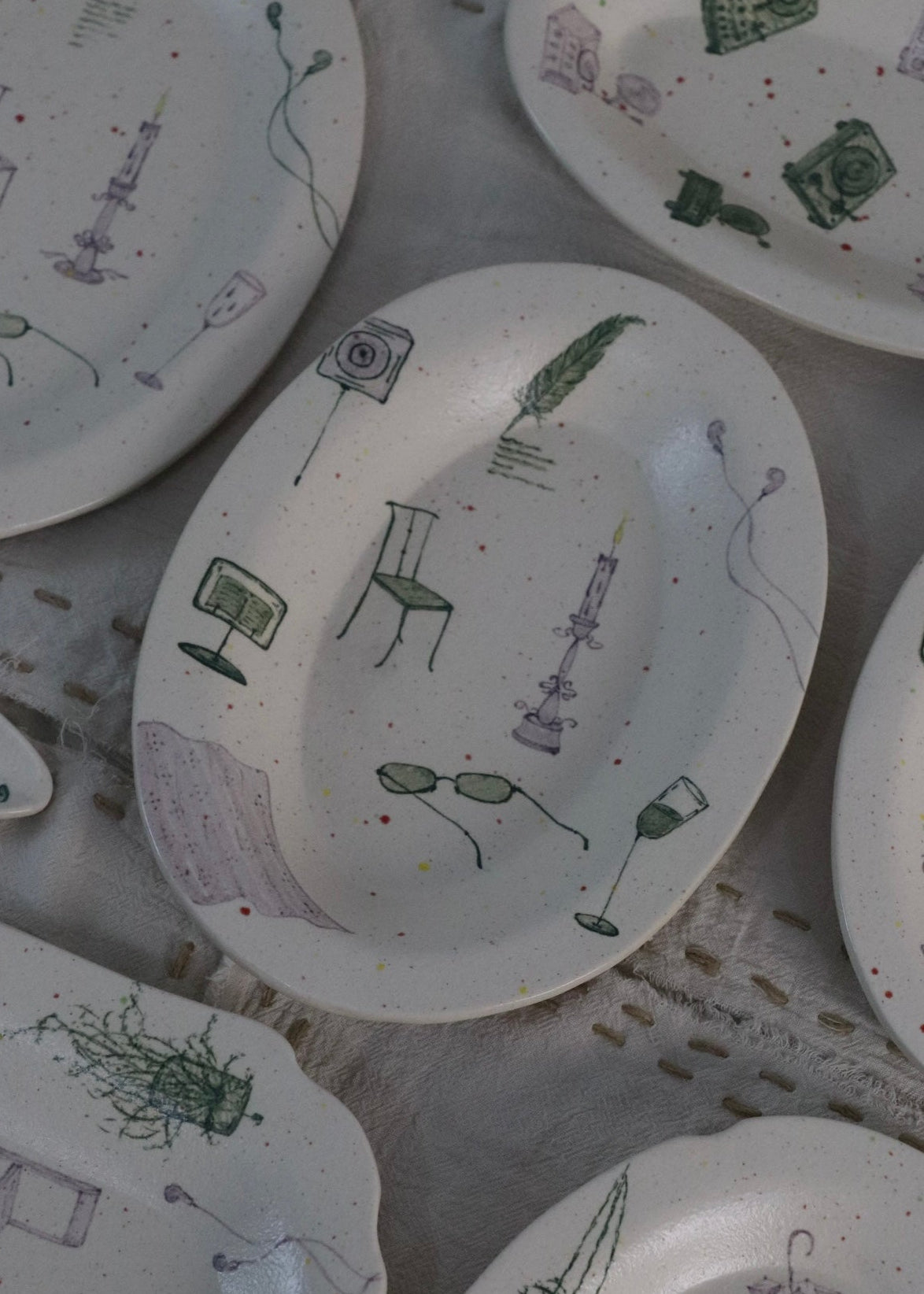 Collection of ceramic plates with artistic designs on a textured surface