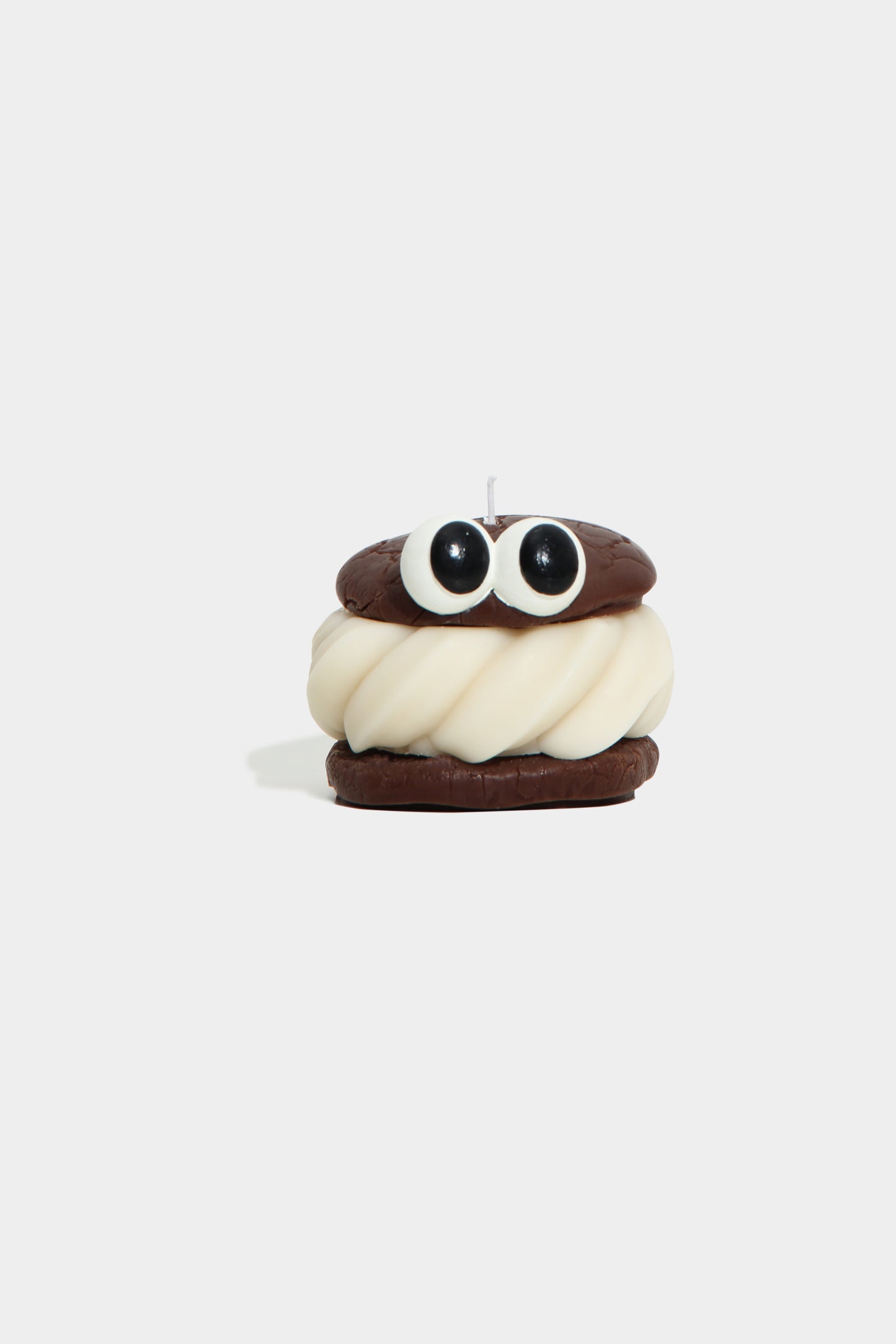 Candle shaped like a cartoon character with a white face and brown hair on a white background