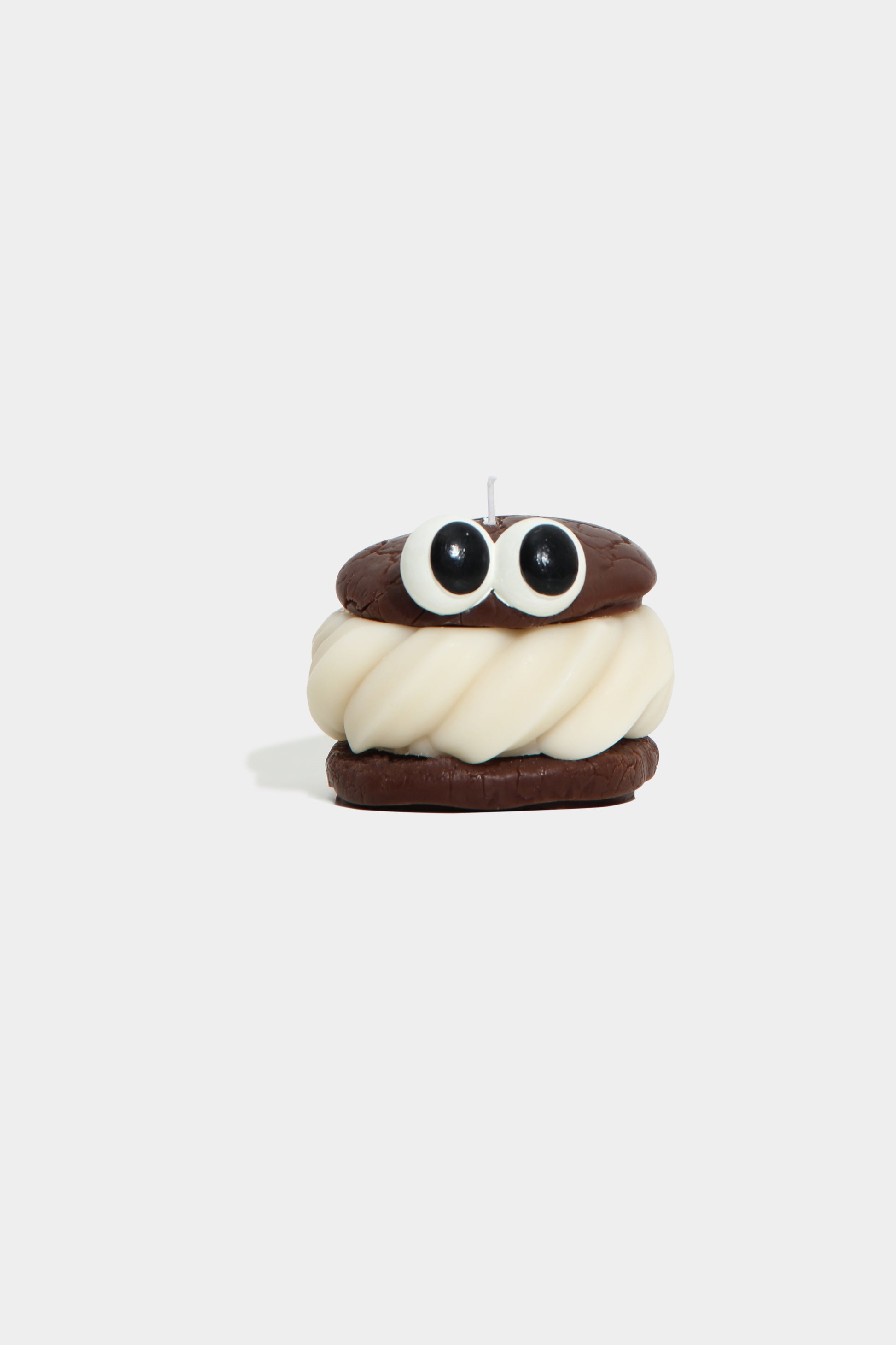 Candle shaped like a cartoon character with a white face and brown hair on a white background