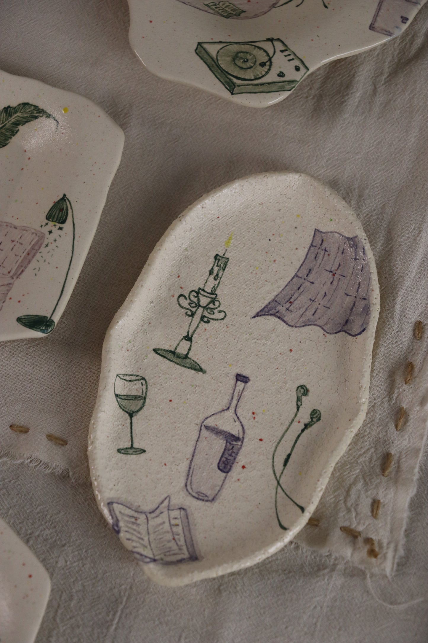 Handmade ceramic plate with wine-themed illustrations on a textured surface.