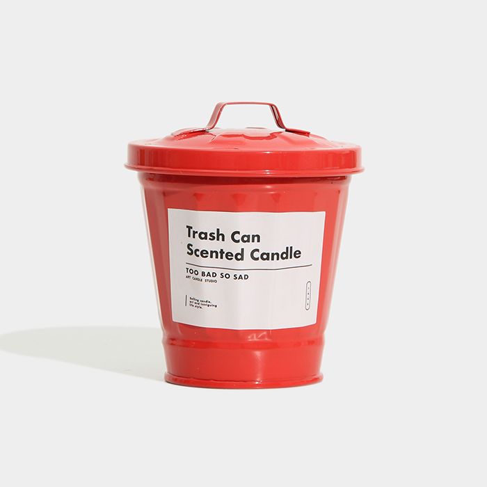 Red trash can-shaped candle with a label on a white background