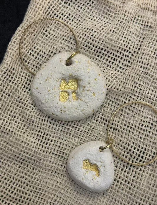 Pair of earrings with gold accents on a textured beige fabric background