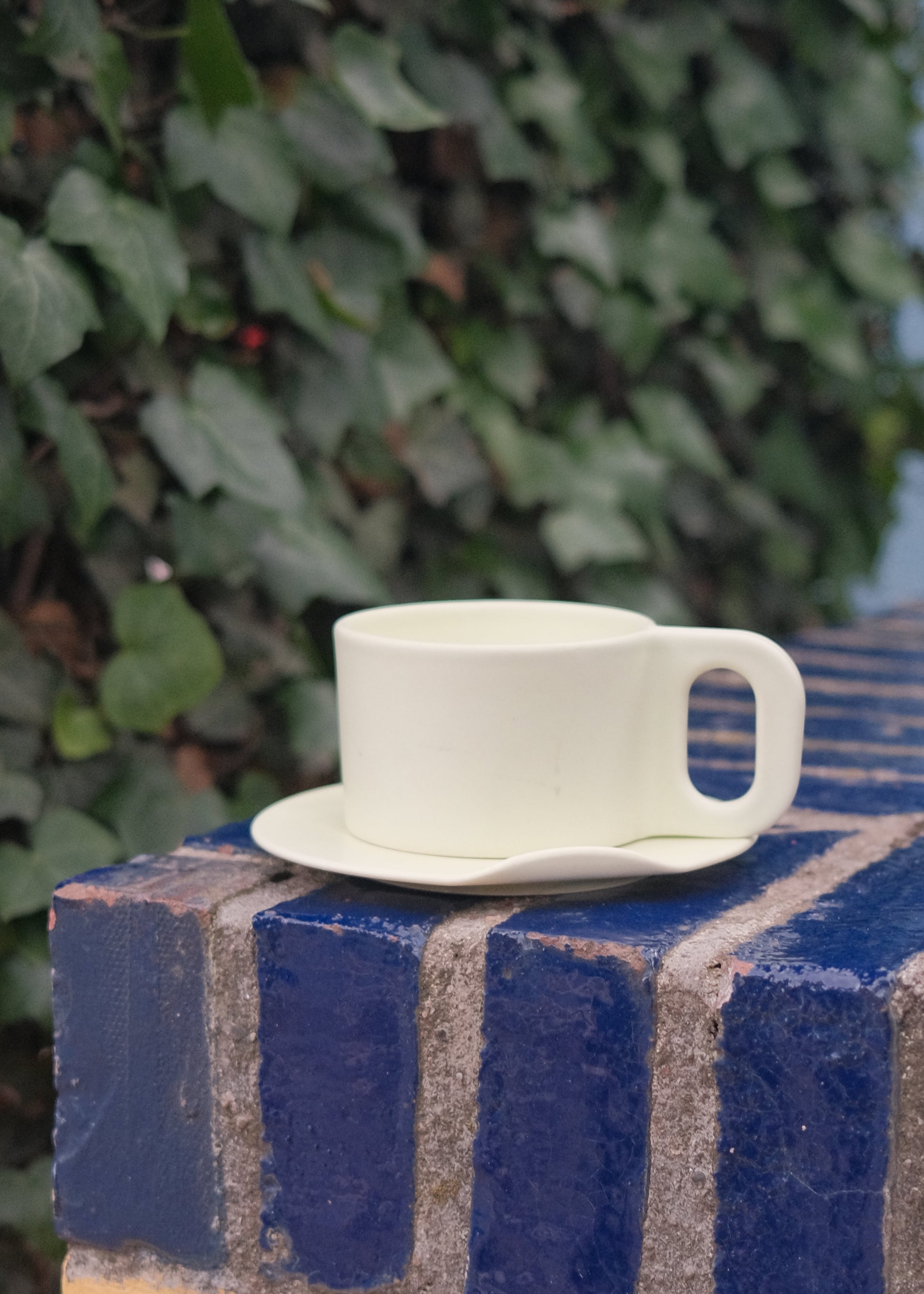 White plastic clip on a blue textured surface with green foliage in the background