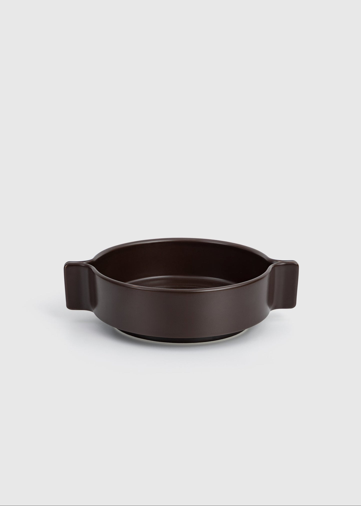 Dark brown ceramic dish with handles on a light gray background
