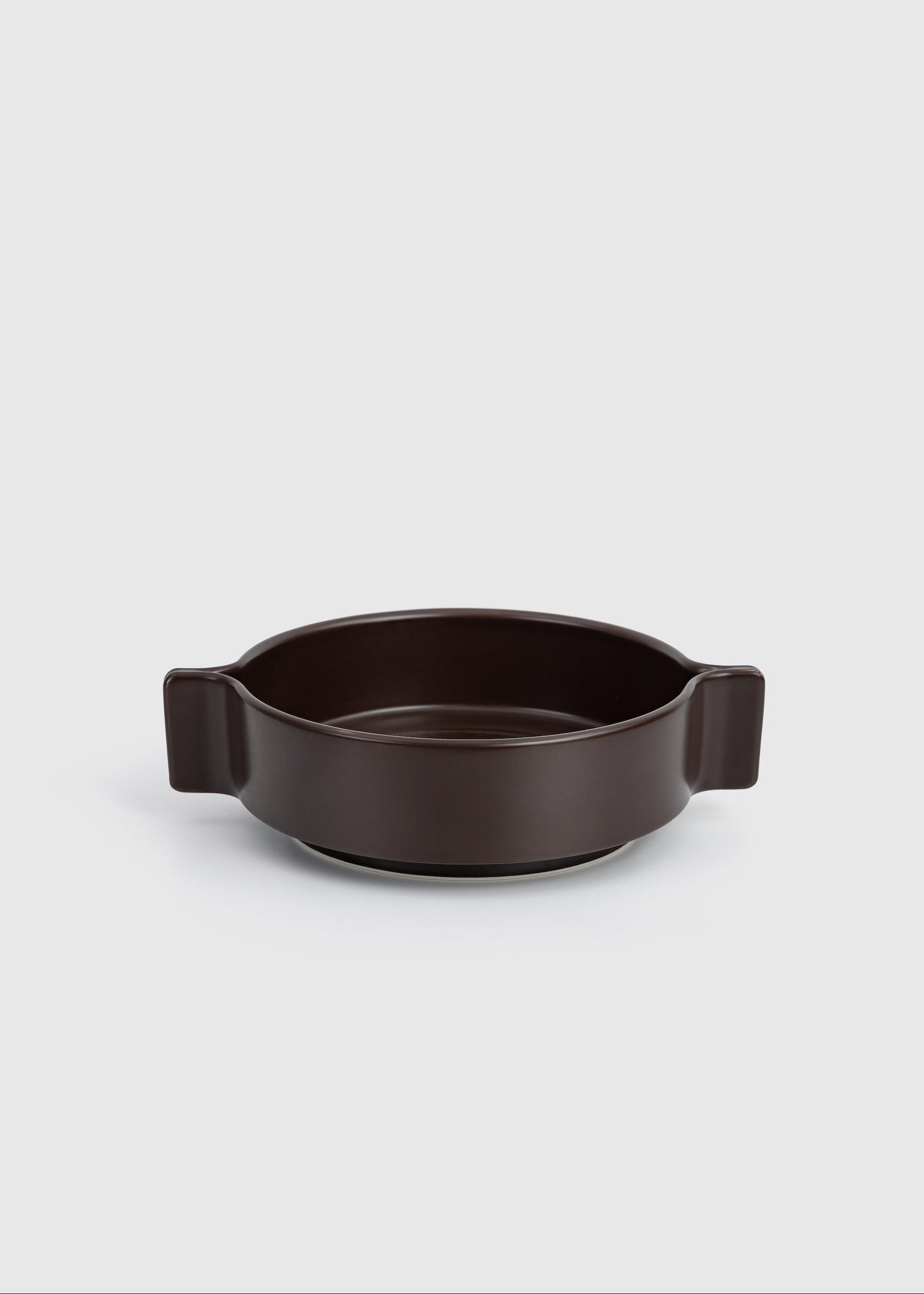 Dark brown ceramic dish with handles on a light gray background