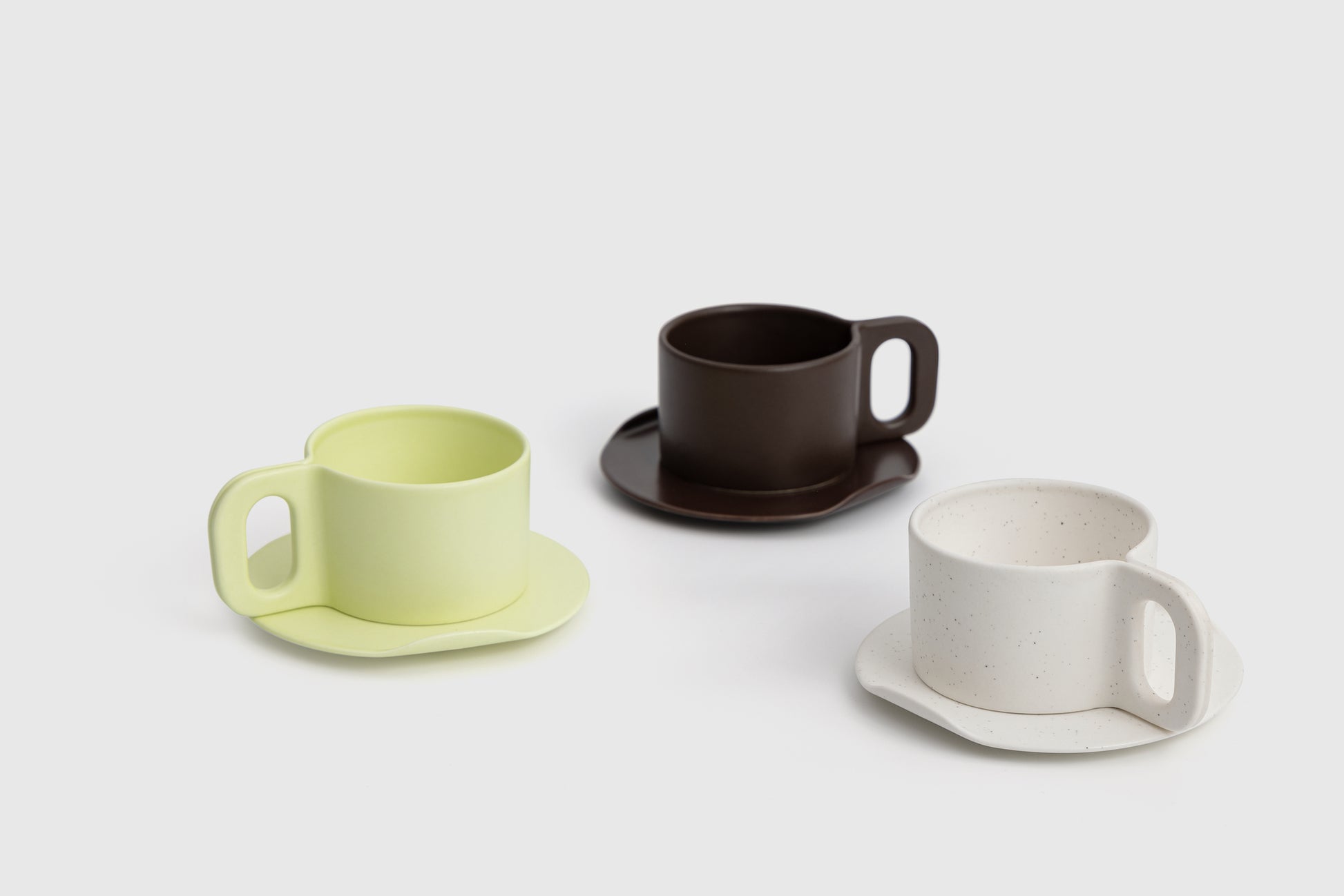 Three ceramic cups with saucers on a light gray background