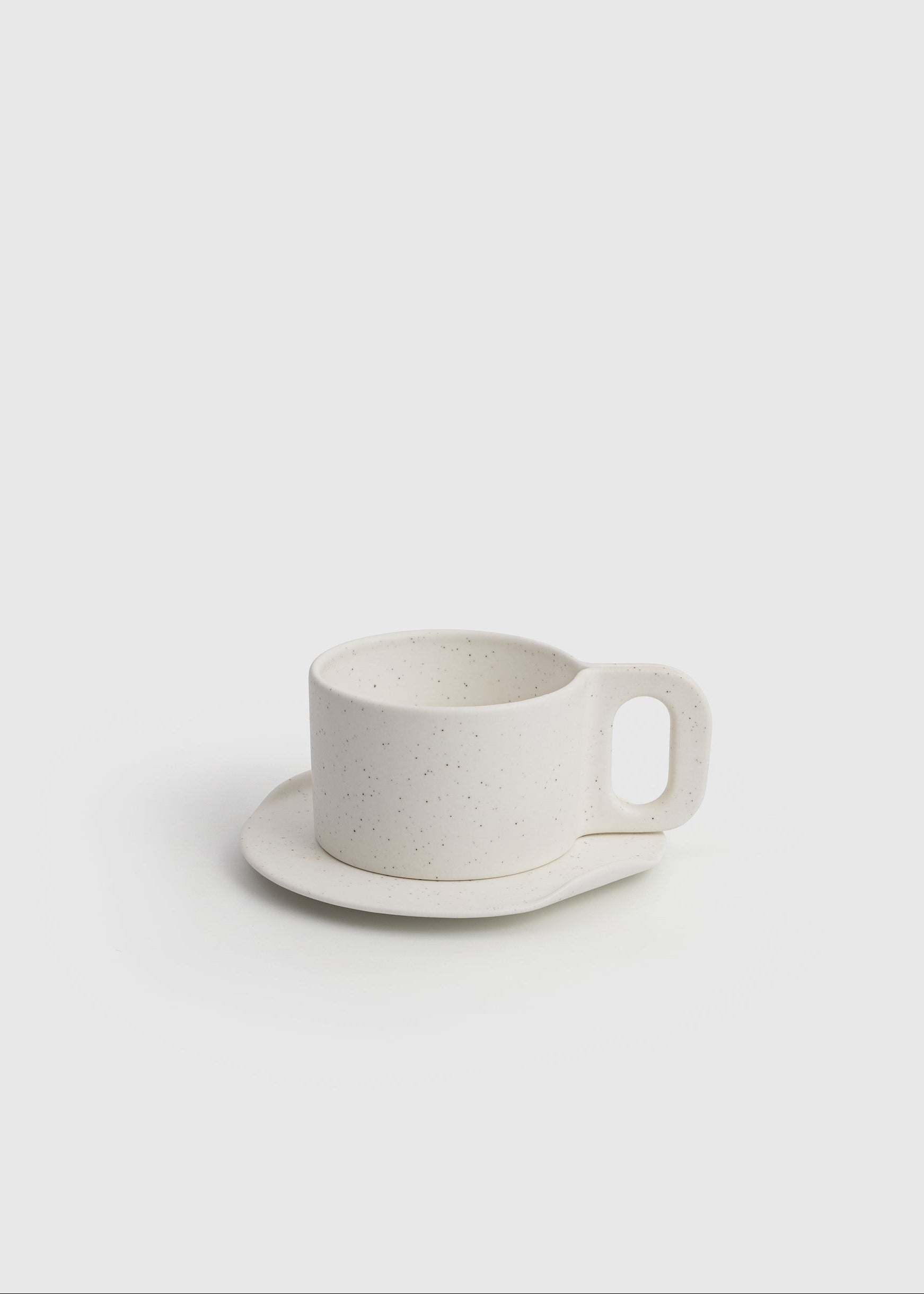 White ceramic cup and saucer on a light gray background