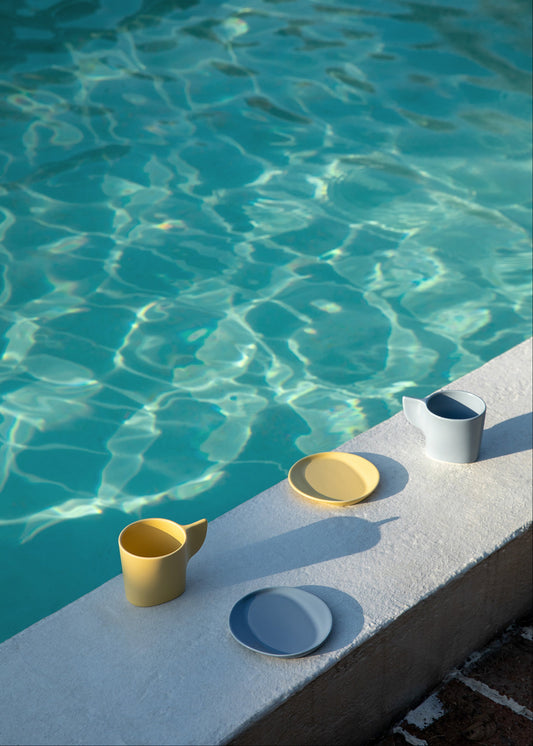 Ceramic items on a poolside ledge with clear blue water.