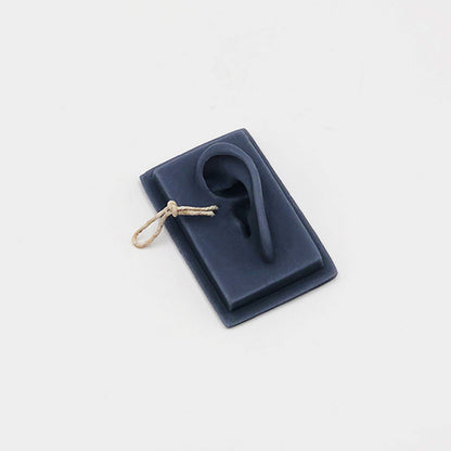 Navy blue silicone earring holder with a single earring on a light gray background