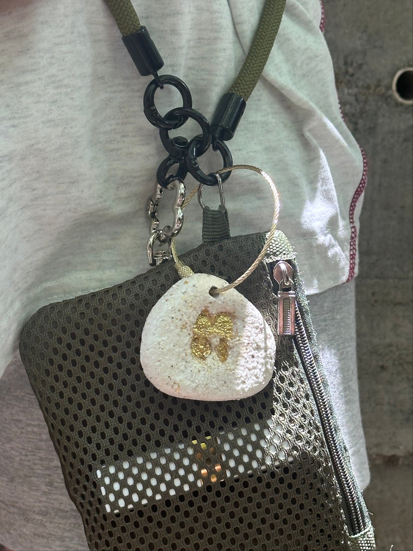 Close-up of a keychain with a textured round tag and heart-shaped charm on a white fabric background.