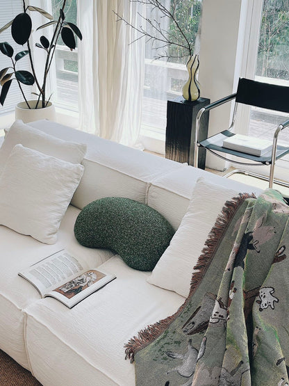 White sofa with decorative pillows and a blanket in a bright living room.