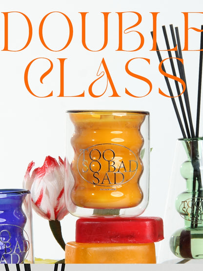 Candle with 'Bad Sia' branding and decorative items on a white background