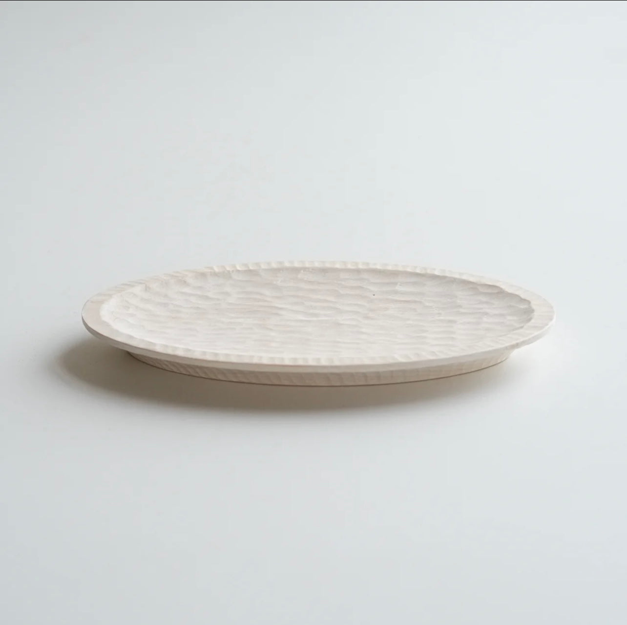 White ceramic plate with textured surface on a light gray background