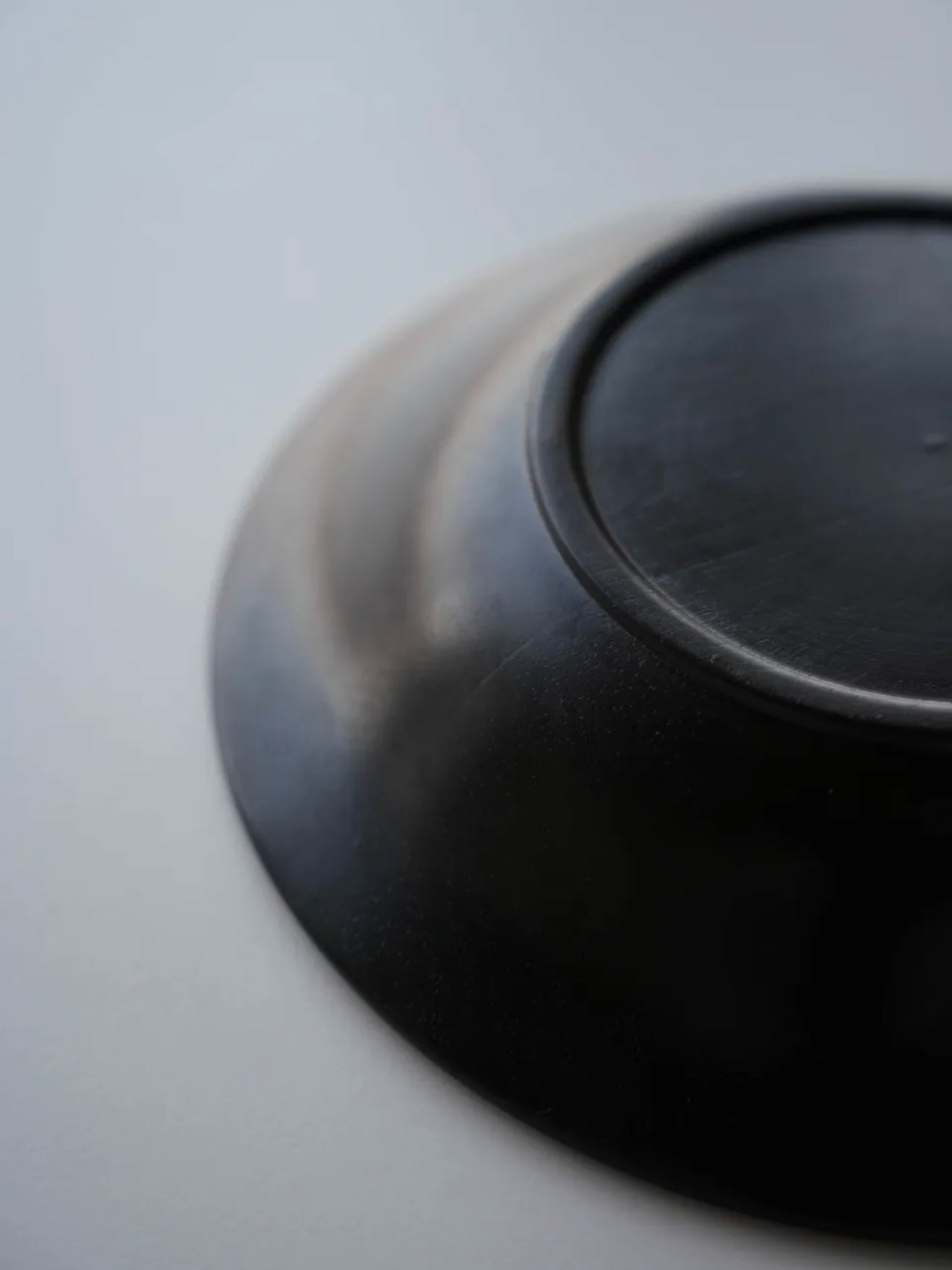 Close-up of a black ceramic plate on a light gray background